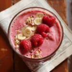 Delicious raspberry smoothie in a glass with fresh raspberries and mint garnish