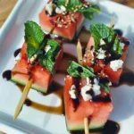 Refreshing watermelon skewers topped with feta cheese, mint leaves, and balsamic glaze.