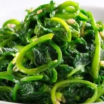 Bowl of Korean Spinach Salad (Sigeumchi Namul) garnished with sesame seeds