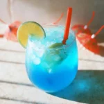 Blue Lagoon Mocktail in a glass with garnishes, showcasing its vibrant blue color.