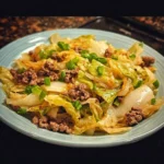 Plate of butter fried cabbage with ground beef, garnished with herbs.