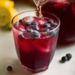 Refreshing homemade blueberry lemonade in a glass with lemon slices and blueberries.